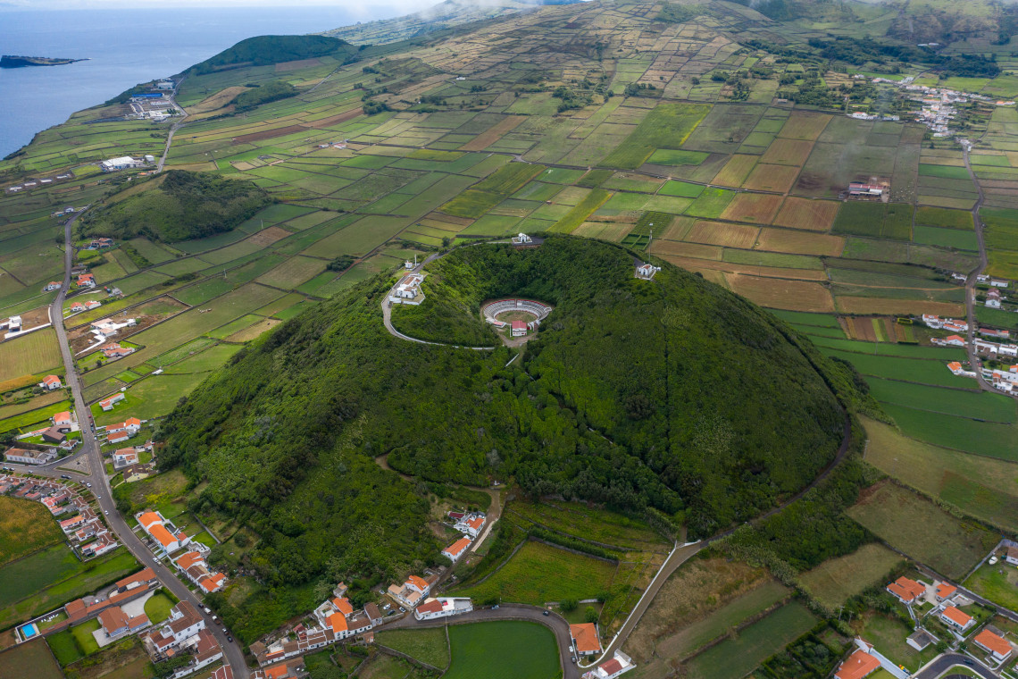 Aerial view of Pra&ccedil;a de Touros da Graciosa set within the green slopes of Monte de Nossa Senhora da Ajuda, surrounded by patchwork farmland near Santa Cruz da Graciosa.