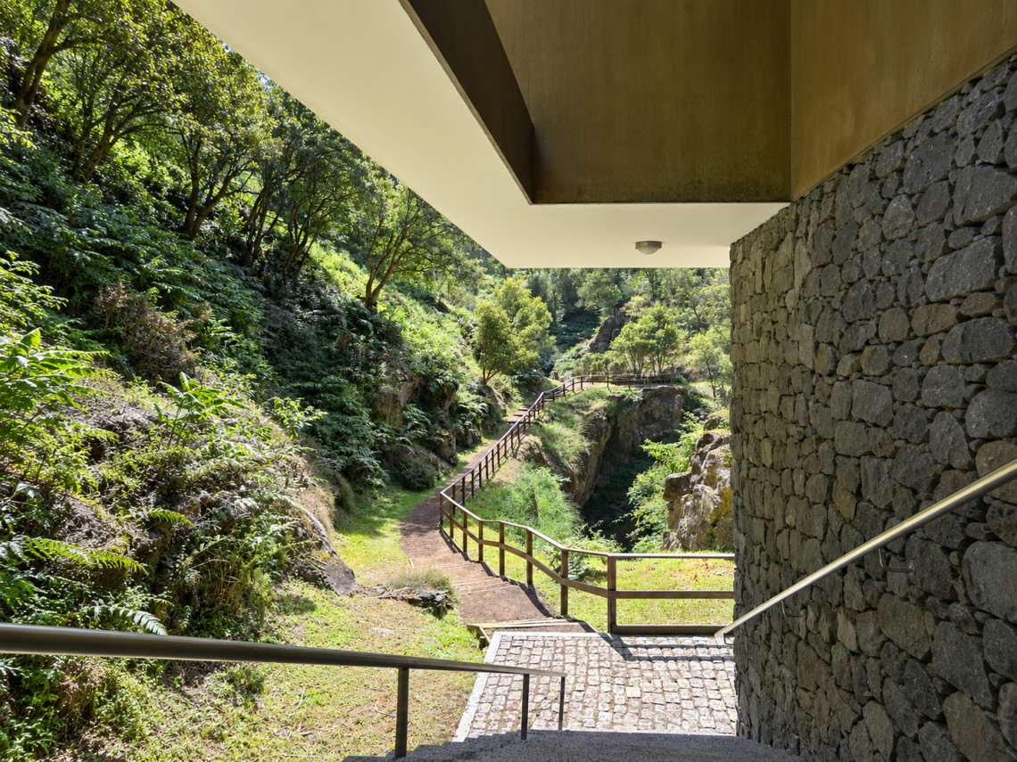Path beside the Furna do Enxofre Visitors Centre on Graciosa Island, with wooden railings leading through dense vegetation toward the volcanic cave inside Caldeira da Graciosa.