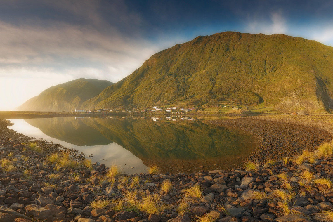 Faj&atilde; da Caldeira de Santo Cristo on S&atilde;o Jorge Island, with its calm coastal lagoon reflecting the steep green volcanic cliffs and small settlement.