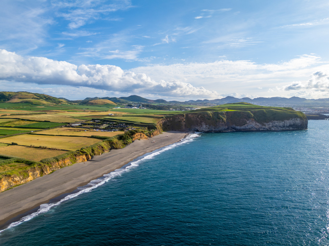 Aerial view of Areal de Santa B&aacute;rbara on S&atilde;o Miguel Island, showing the long volcanic sand beach, Atlantic Ocean and green agricultural fields along the coast.