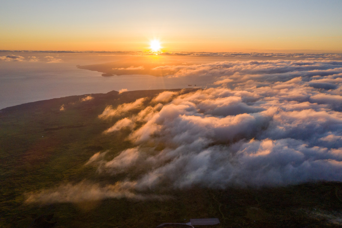 Aerial view from the summit of Mount Pico at sunset, looking out above a sea of clouds over Pico Island and the Atlantic Ocean, the highest point in Portugal, Azores