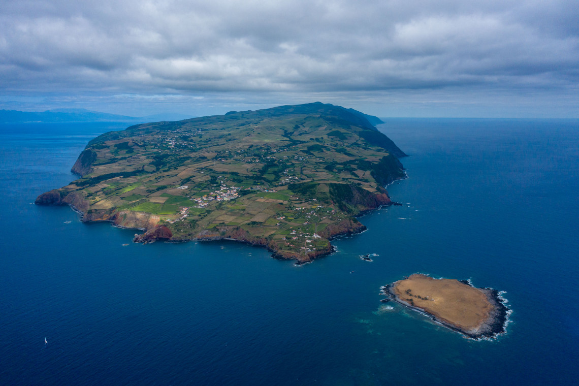 Aerial view of the eastern end of S&atilde;o Jorge Island in the Azores, showing patchwork farmland, volcanic cliffs and Ilh&eacute;u do Topo surrounded by the Atlantic Ocean.