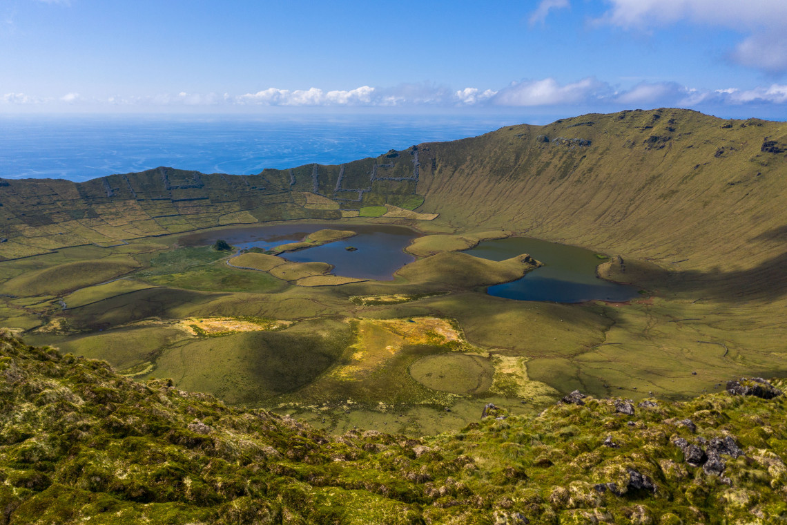 Panoramic view across Caldeir&atilde;o Crater on Corvo Island in the Azores, Portugal. Small crater lakes and rounded volcanic formations spread across the green caldera floor beneath steep surrounding slopes.