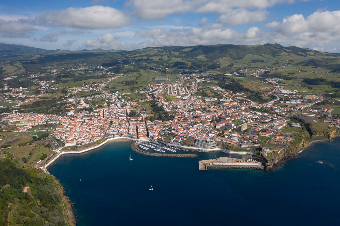 Aerial view from above Angra Bay showing the red-roofed city of Angra do Hero&iacute;smo, its marina and harbor surrounded by the green hills of Terceira Island.