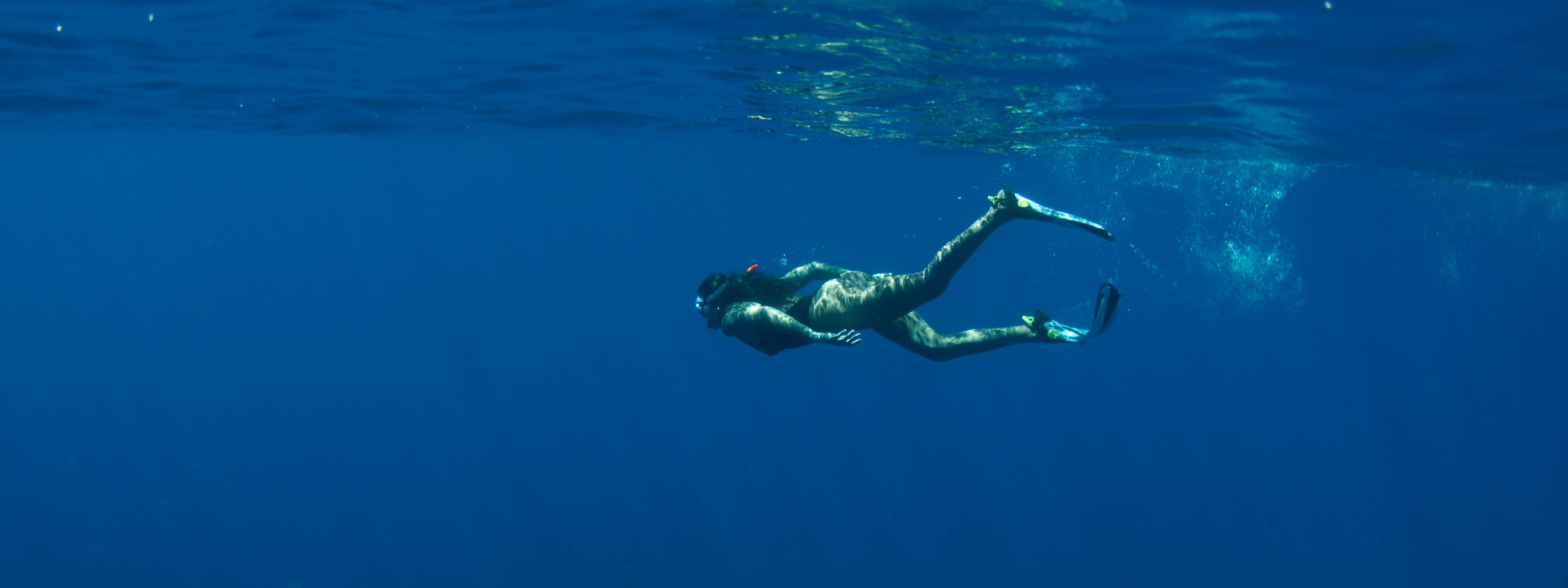 Freediver swimming beneath the surface of the Atlantic Ocean off Santa Maria Island in the Azores.