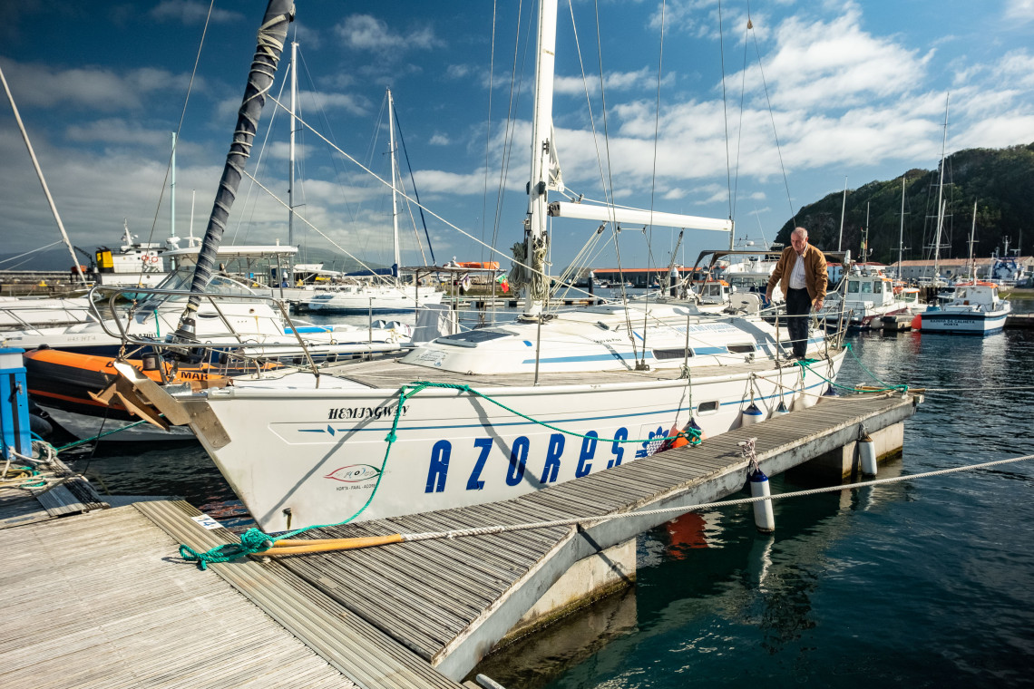 Sailing boat moored at Horta Marina on Faial Island in the Azores, Portugal, surrounded by yachts and harbor pontoons.