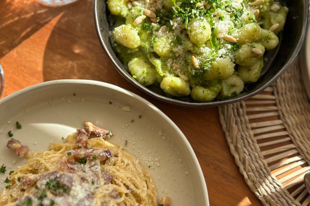 Platos de pasta con pesto verde y salsa cremosa servidos en una mesa de restaurante en S&atilde;o Miguel Island, Azores.
