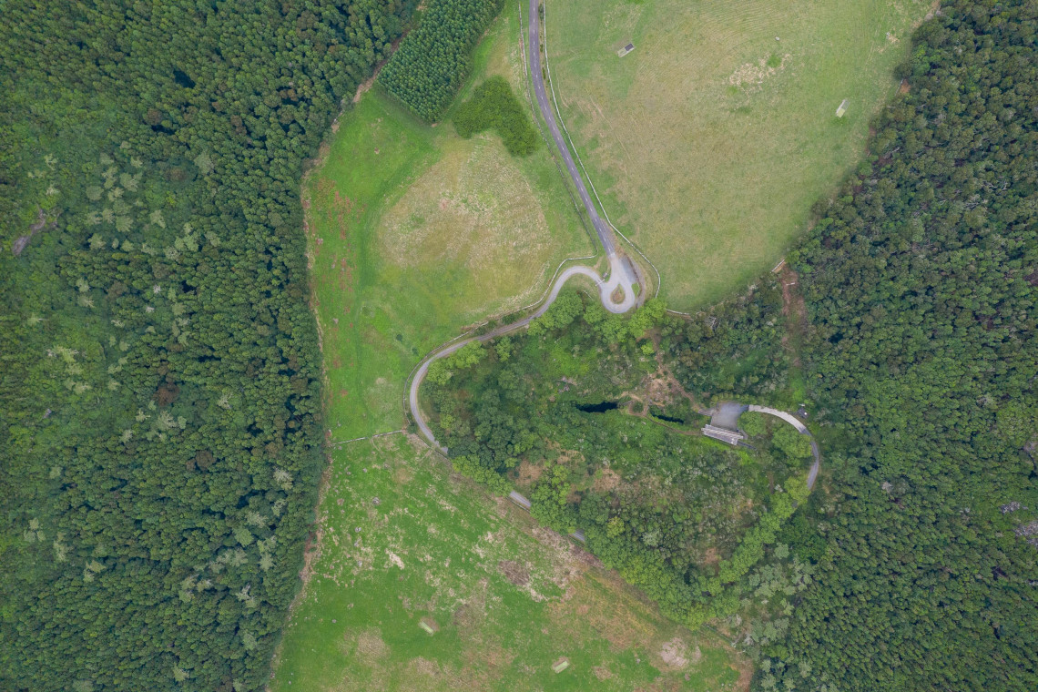 Aerial view over the green interior of Caldeira da Graciosa, with the Furna do Enxofre area, winding access road and surrounding forest visible within the volcanic crater.