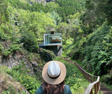Traveler approaching the Furna do Enxofre Visitors Centre in São Mateus on Graciosa Island, surrounded by dense vegetation inside the Caldeira da Graciosa. The center provides access to the volcanic cave below.