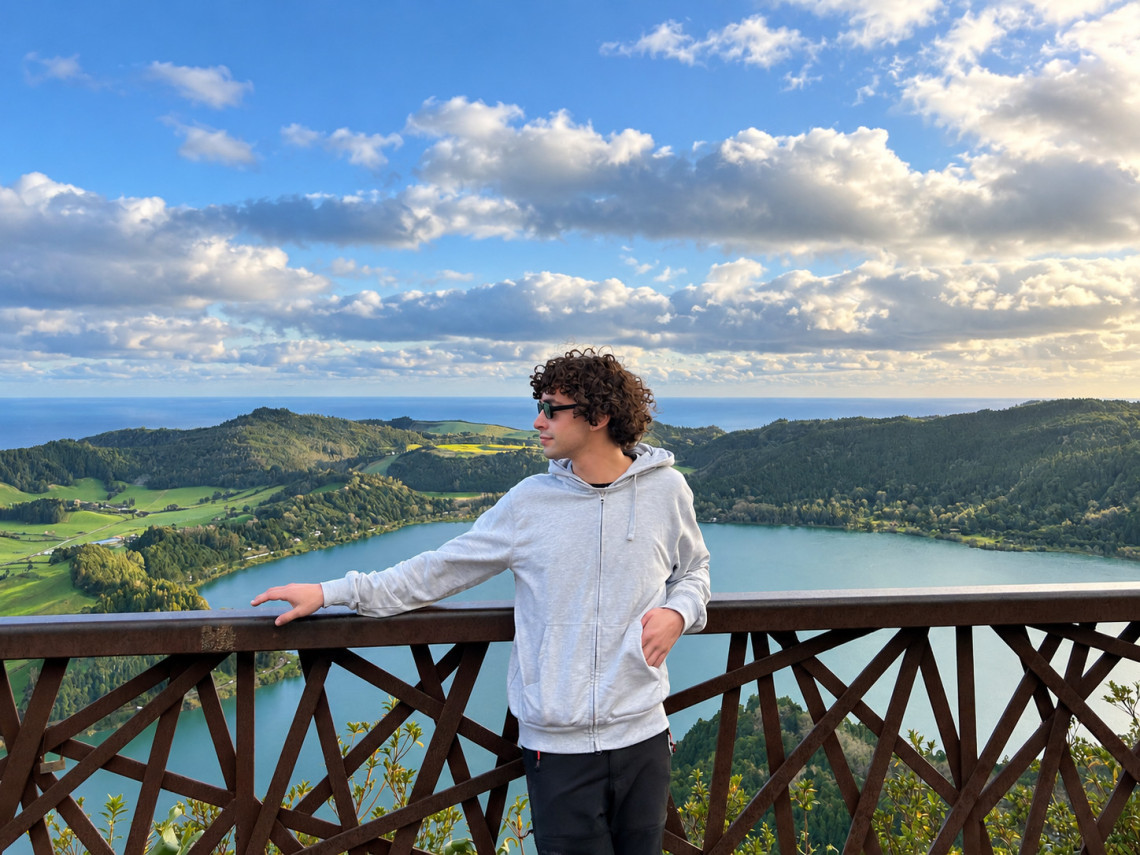 Visitor overlooking the Furnas caldera from Miradouro do Pico do Ferro, with Lagoa das Furnas, green pastures and volcanic hills extending toward the Atlantic.