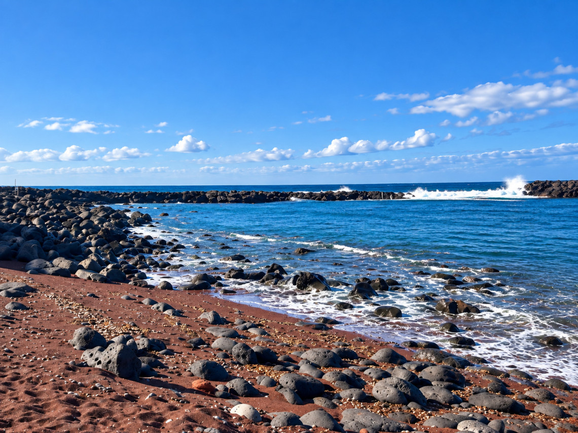 Barro Vermelho Beach on Graciosa Island, with reddish volcanic sand, rounded basalt stones and Atlantic waves breaking along the shore.