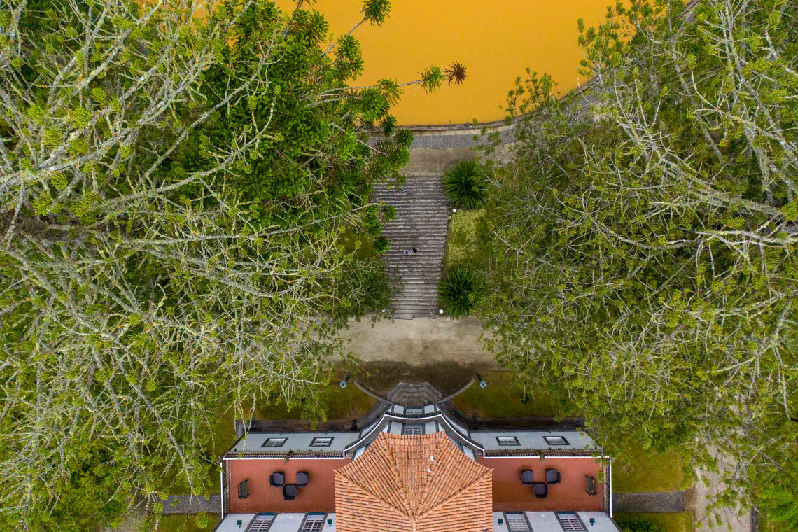 Top-down aerial view of Terra Nostra Park in Furnas, with its iron-rich thermal pool, historic building and mature botanical gardens on S&atilde;o Miguel Island.