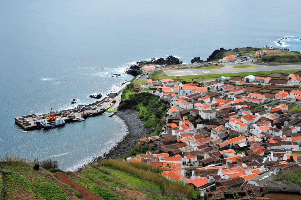Aerial view of Vila do Corvo on the southern coast of Corvo Island in the Azores, Portugal. The compact village, harbour and nearby airfield occupy the island&rsquo;s low volcanic faj&atilde; beside the Atlantic Ocean.