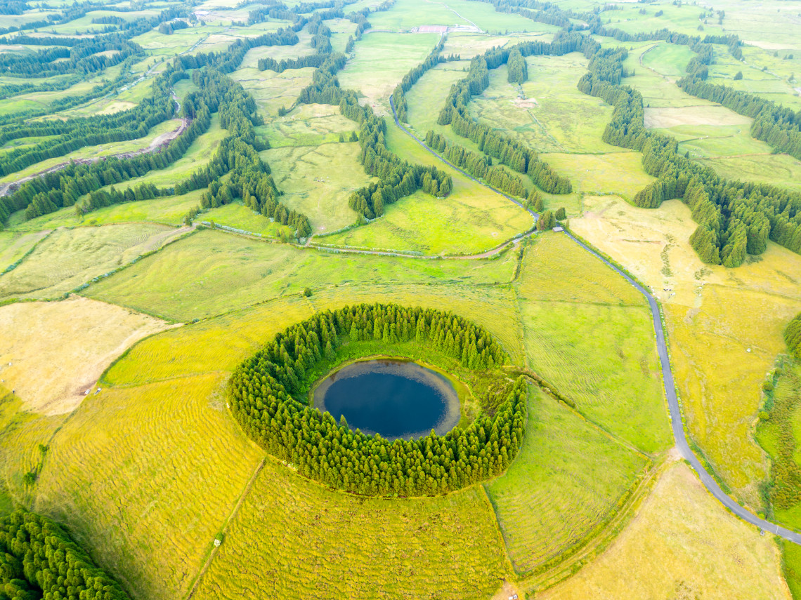 Aerial view of Lagoa do Pique-Pau in Serra Devassa on S&atilde;o Miguel Island, a small volcanic lagoon surrounded by trees and open green pastureland.