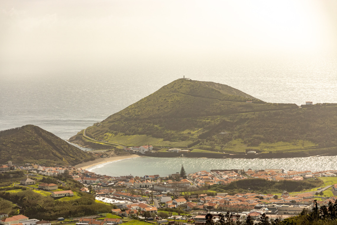 Panoramic view over Porto Pim in Horta, Faial, with its curved bay and red-roofed neighborhood beneath the volcanic slopes of Monte da Guia.