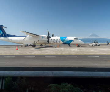 SATA Air Açores aircraft parked at São Jorge Airport in the Azores, Portugal, with Mount Pico visible across the Atlantic channel in the distance.
