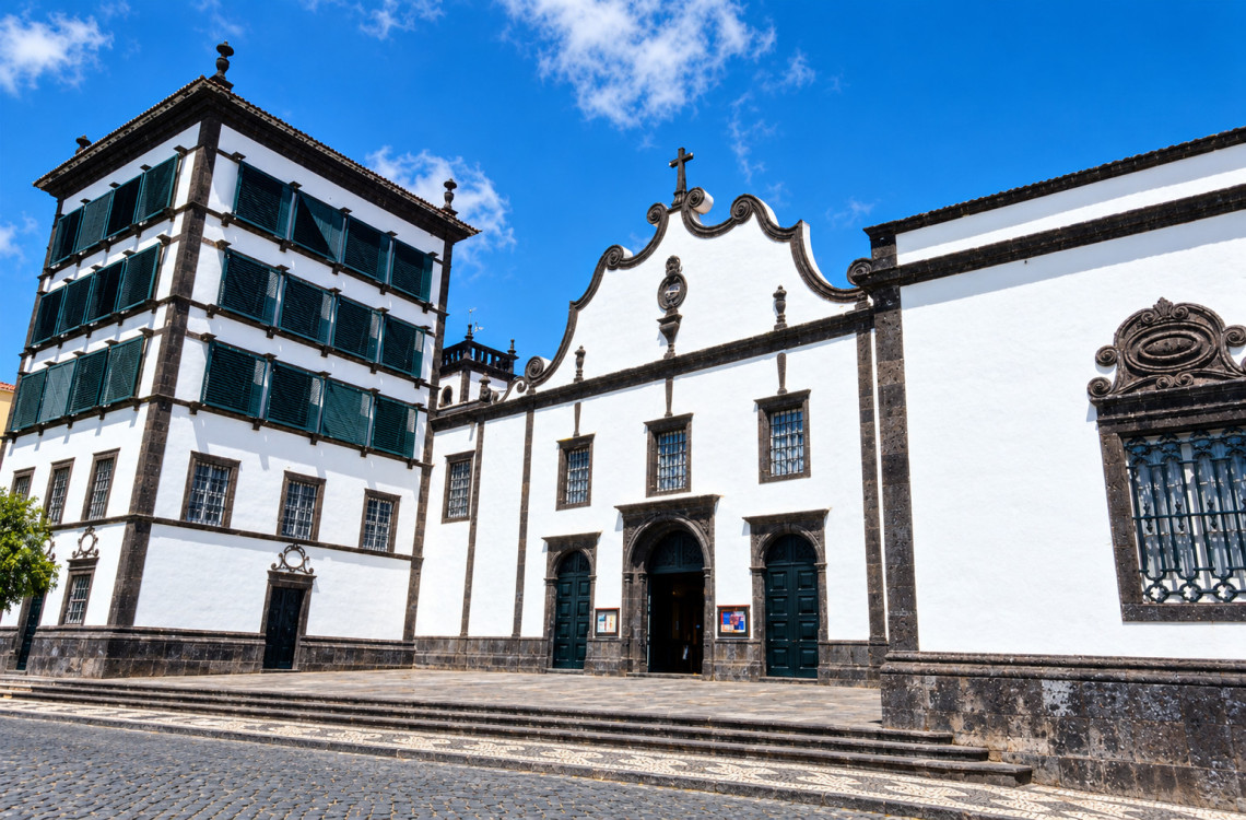 Exterior of the historic Convento da Esperan&ccedil;a in Ponta Delgada, featuring traditional white walls, dark volcanic stone details and green shutters.