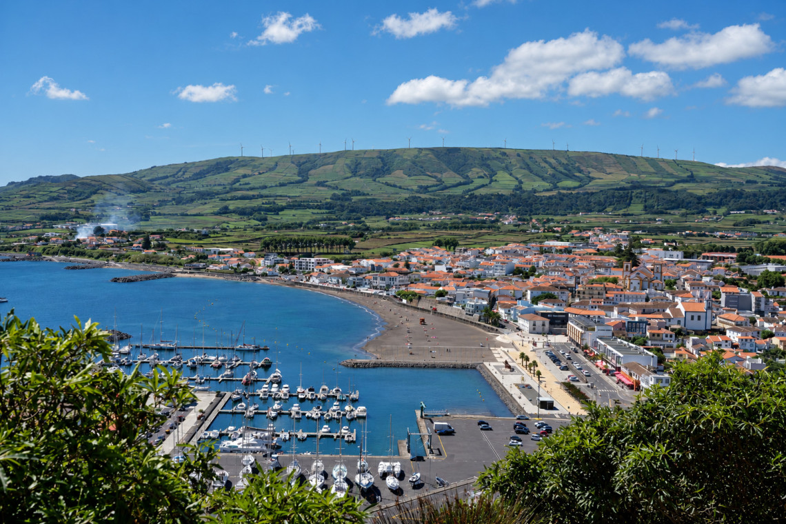 Panoramic view from Miradouro do Facho over Praia da Vit&oacute;ria, showing the marina, sandy beach, town and green hills surrounding the Atlantic bay.