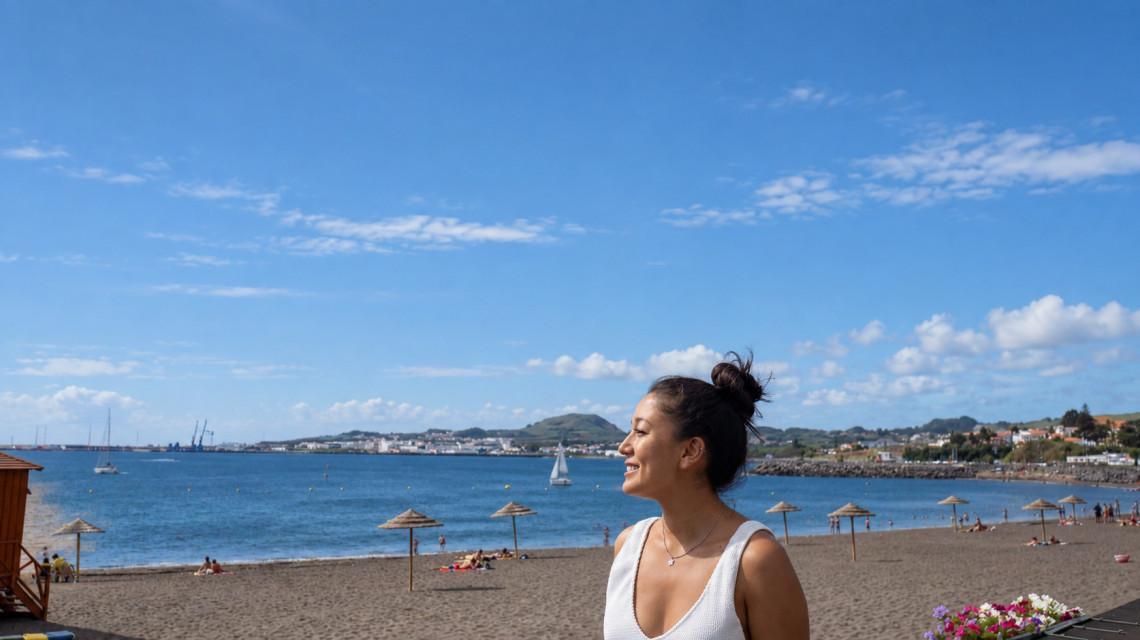 Woman overlooking Praia Grande in Praia da Vit&oacute;ria on Terceira Island, with the sandy beach, calm blue bay and coastal town in the background.