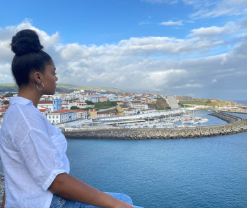 Woman enjoying the panoramic view over Angra do Heroísmo marina and colourful waterfront on Terceira Island, Azores, Portugal
