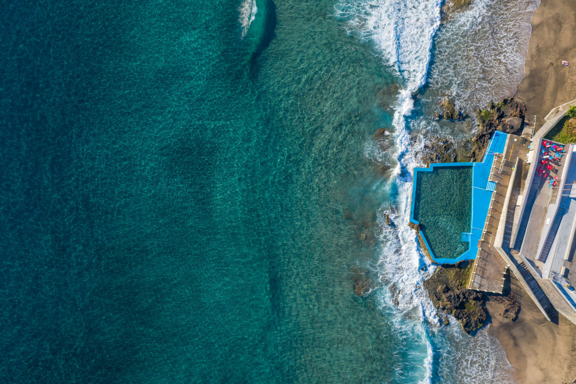 Overhead aerial view of the natural swimming pool at Maia on Santa Maria Island, built into the volcanic shoreline beside clear turquoise Atlantic waters.