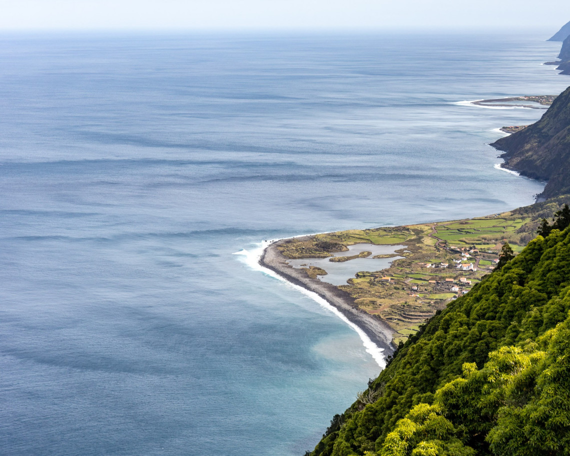 Elevated view of Faj&atilde; dos Cubres on S&atilde;o Jorge Island, showing its coastal lagoon, cultivated fields and scattered houses beside the Atlantic Ocean.