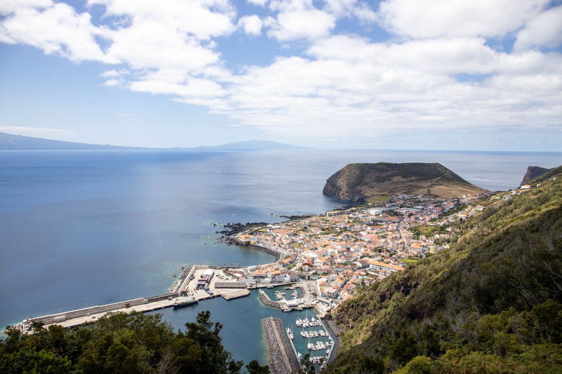 Panoramic view from Miradouro das Velas over the town of Velas on S&atilde;o Jorge Island, showing its marina, harbor, red-roofed buildings and the volcanic Morro das Velas beside the Atlantic Ocean.