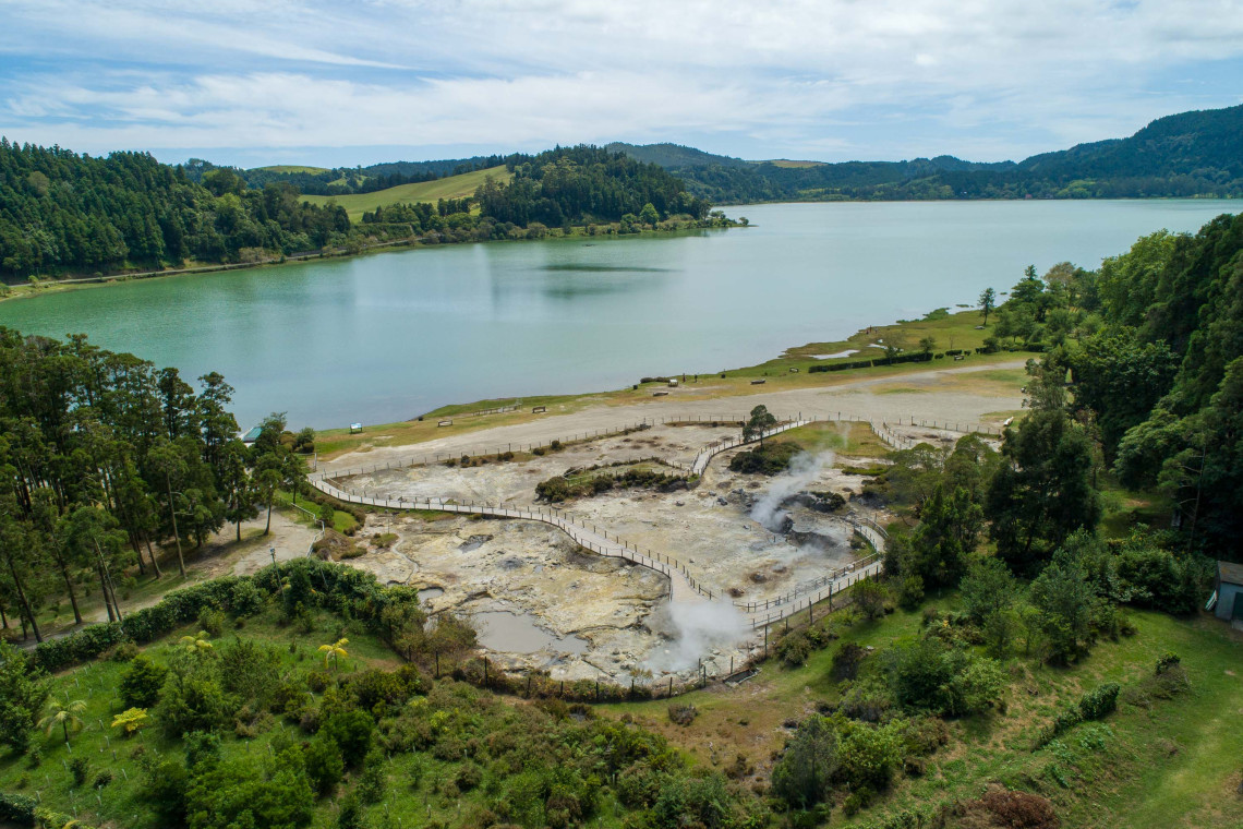 Elevated view of Lagoa das Furnas and its geothermal area, with steaming fumaroles along the shore of the volcanic crater lake.