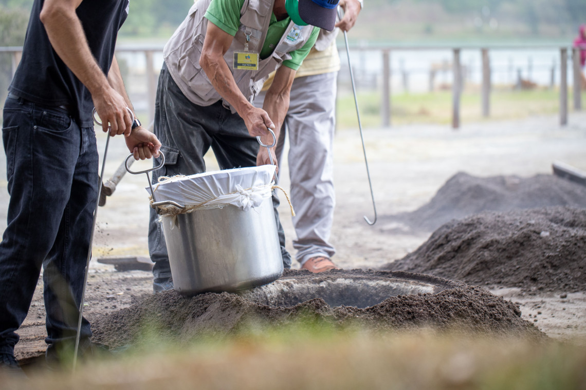 Workers lifting a pot of Cozido das Furnas from a geothermal cooking hole in Furnas, S&atilde;o Miguel Island, where the traditional Azorean stew is slowly cooked underground using natural volcanic heat.