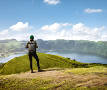 Persona de pie en un mirador durante una ruta de senderismo en Sete Cidades, con vista a la laguna volcánica en la isla de São Miguel, Azores
