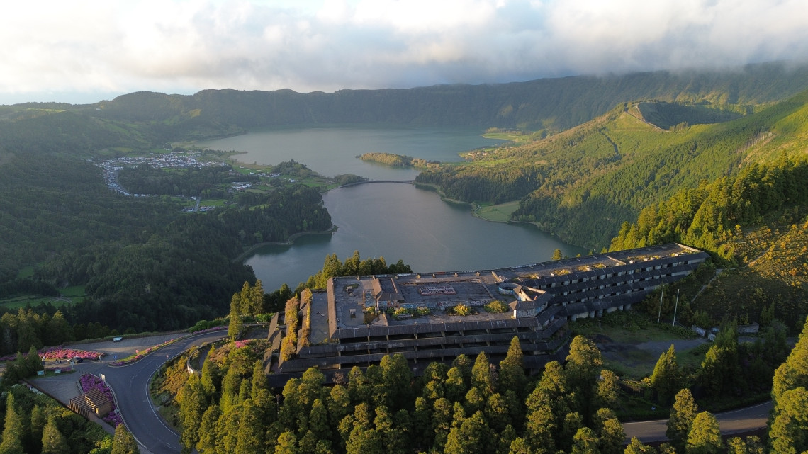 Aerial view over Vista do Rei and the abandoned Monte Palace Hotel, with the Sete Cidades crater lakes and forested volcanic walls in the background.