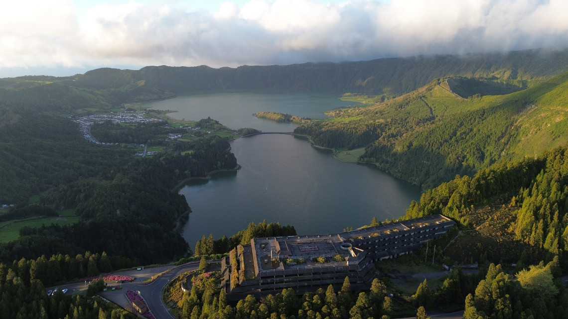 Elevated view from Vista do Rei over the Sete Cidades crater lakes, with Lagoa Azul and Lagoa Verde surrounded by forested volcanic slopes. The former Monte Palace hotel appears in the foreground.