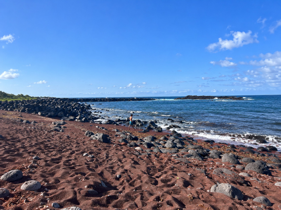 Barro Vermelho Beach on Graciosa Island, with reddish volcanic sand, rounded dark basalt stones and Atlantic waves along the shoreline.