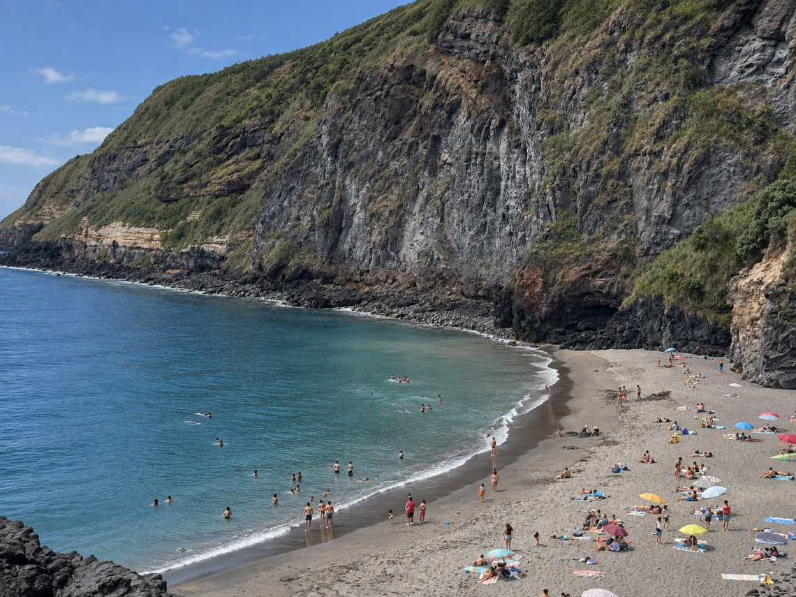 Praia da Caloura, also known as Baixa d&rsquo;Areia, in &Aacute;gua de Pau on S&atilde;o Miguel Island, with dark volcanic sand, clear Atlantic water and the green coastal landscape of the Azores.