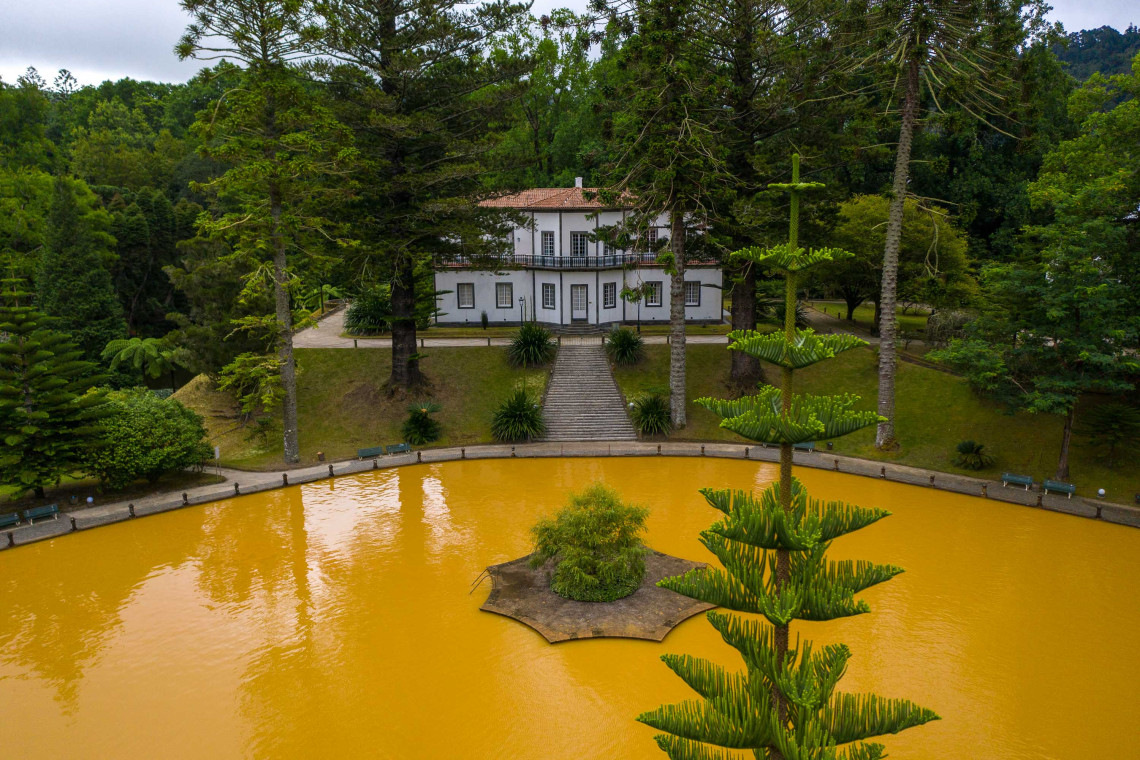 Aerial view of the iconic iron-rich orange thermal pool and historic villa surrounded by lush subtropical gardens at Terra Nostra Park in Furnas, S&atilde;o Miguel Island, Azores, Portugal