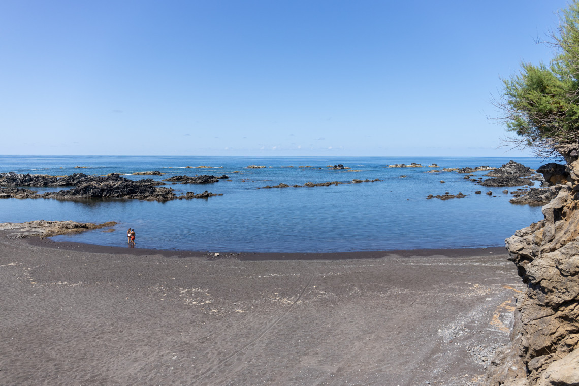 Praia da Areia in Vila do Corvo features dark volcanic sand and a sheltered stretch of Atlantic water bordered by basalt rock formations. It is the main beach area on Corvo Island in the Azores, Portugal.