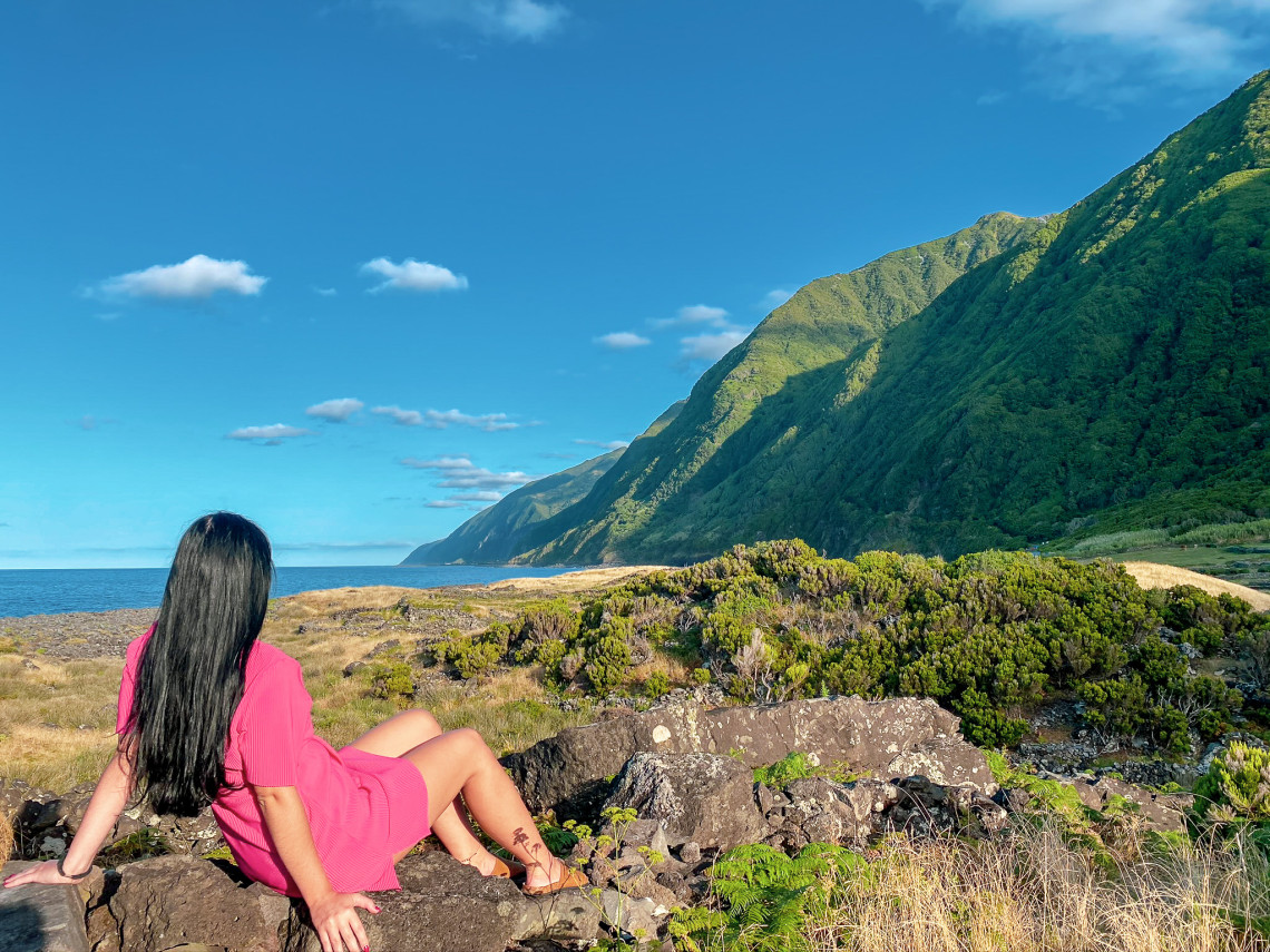 Traveler overlooking the rugged coast of S&atilde;o Jorge Island, where steep green volcanic cliffs extend along the deep blue Atlantic Ocean.