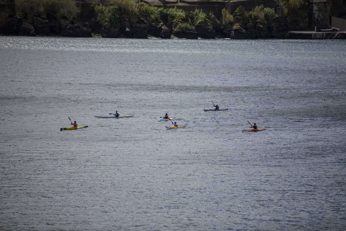 Group of kayakers paddling across calm coastal waters near Velas on S&atilde;o Jorge Island in the Azores.