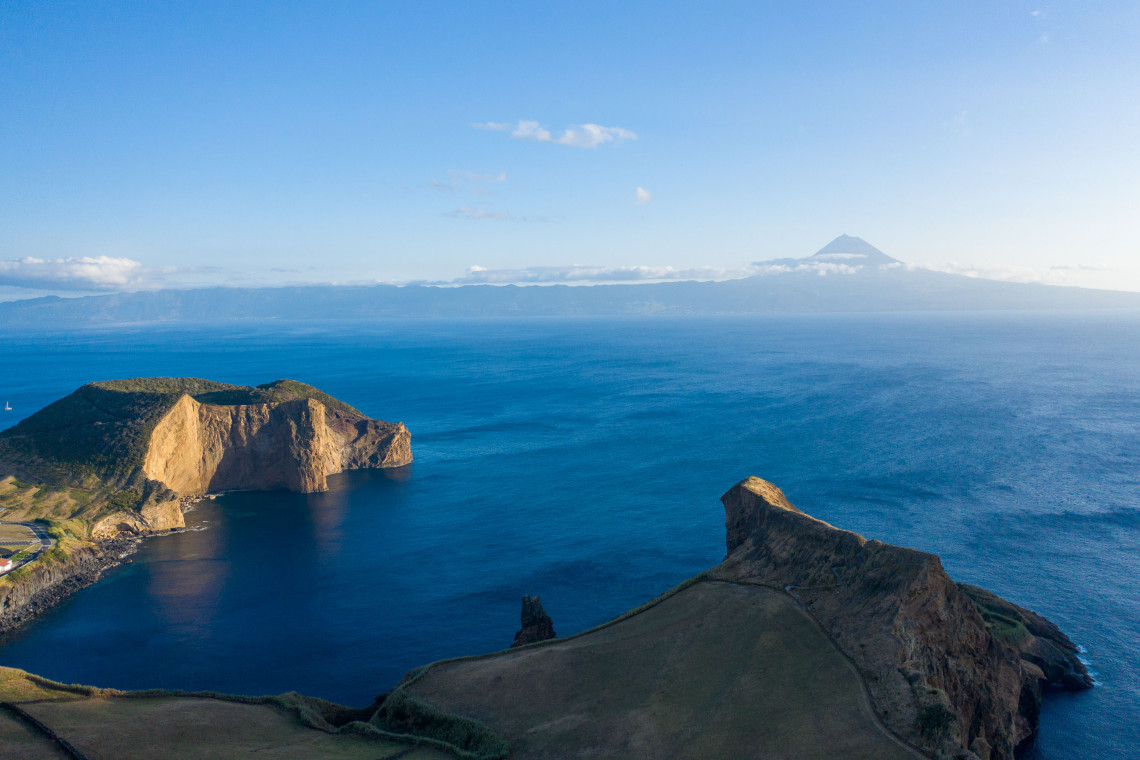 Elevated view across the volcanic formations of Morro de Velas and Morro de Lemos on S&atilde;o Jorge Island, with the Atlantic channel and Mount Pico rising in the distance.