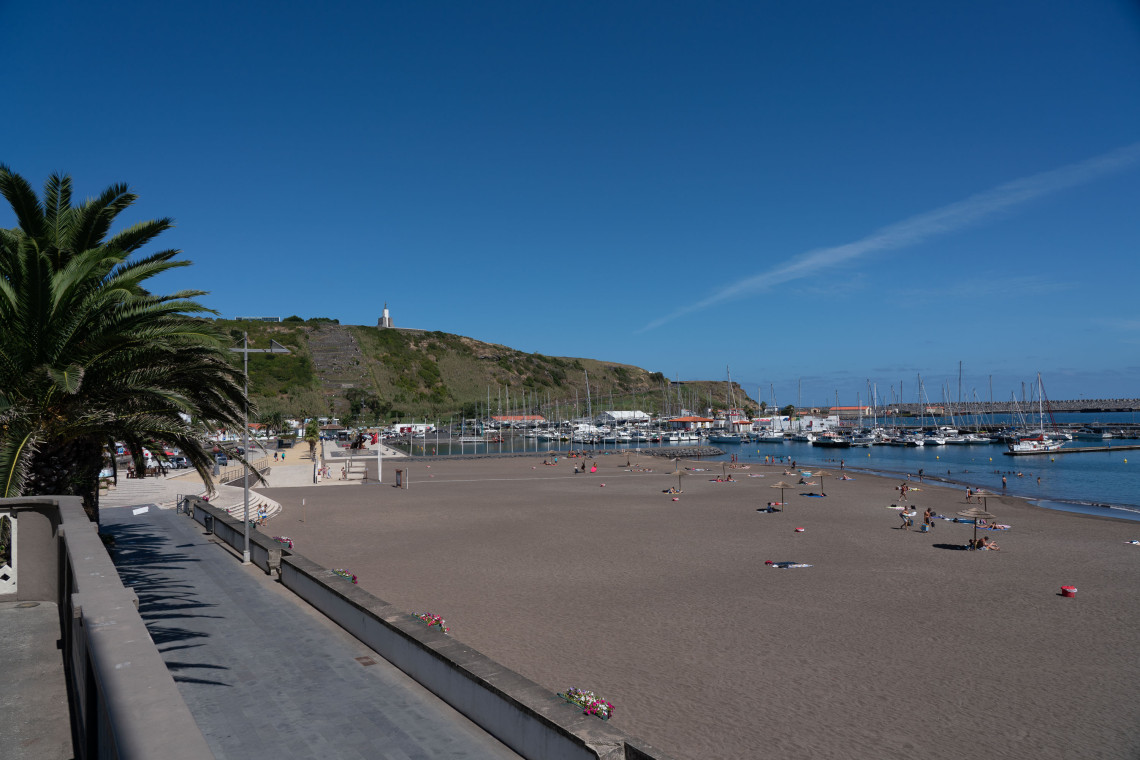 Praia Grande in Praia da Vit&oacute;ria on Terceira Island, with its broad sandy shoreline beside the marina, waterfront promenade and palm trees.