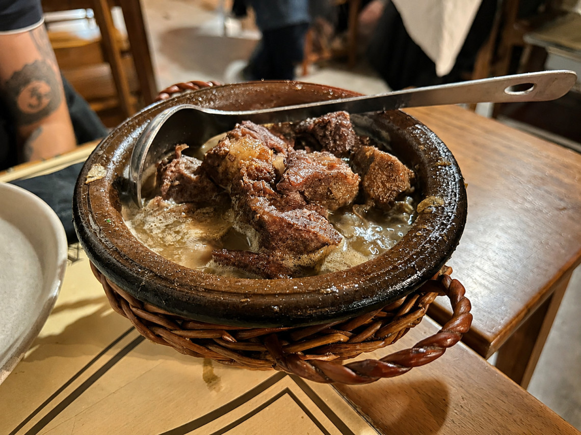 Traditional alcatra da Terceira served in a clay pot, with large pieces of slow-cooked beef in a rich cooking broth at a local Azorean restaurant.