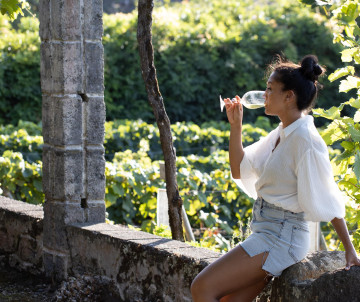 Traveler tasting local Azorean wine in Biscoitos on Terceira Island, surrounded by vineyards and traditional volcanic-stone walls.