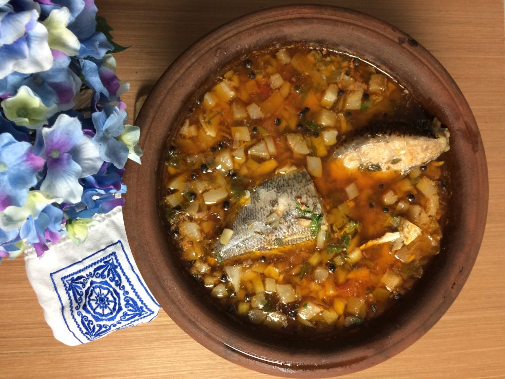 Traditional Azorean fish stew served in a clay bowl, with pieces of fish cooked in a broth with diced vegetables and herbs on Terceira Island.