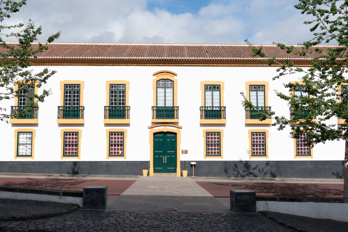 Front fa&ccedil;ade of the Pal&aacute;cio dos Capit&atilde;es-Generais in Angra do Hero&iacute;smo on Terceira Island, featuring white walls, ochre window surrounds, green shutters and a central entrance facing a paved courtyard.