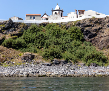 The whitewashed Church of Nossa Senhora dos Milagres stands above the rocky coastline of Vila do Corvo on Corvo Island in the Azores, Portugal. The late-18th-century church is dedicated to the island’s patron saint.