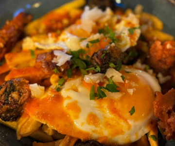 Pico Island dish served with a fried egg, vegetables, herbs and seasoned accompaniments at a restaurant in Madalena, highlighting local Azorean cuisine.