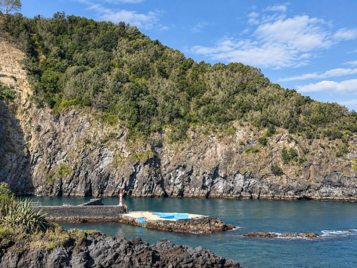 Porto da Caloura on the southern coast of S&atilde;o Miguel Island, with a sheltered harbor, volcanic rock cliffs and clear Atlantic water.