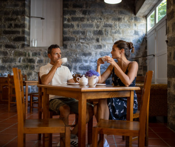 Couple enjoying a traditional tea tasting in a rustic stone interior on São Miguel Island, surrounded by the warm atmosphere of an Azorean tea experience.