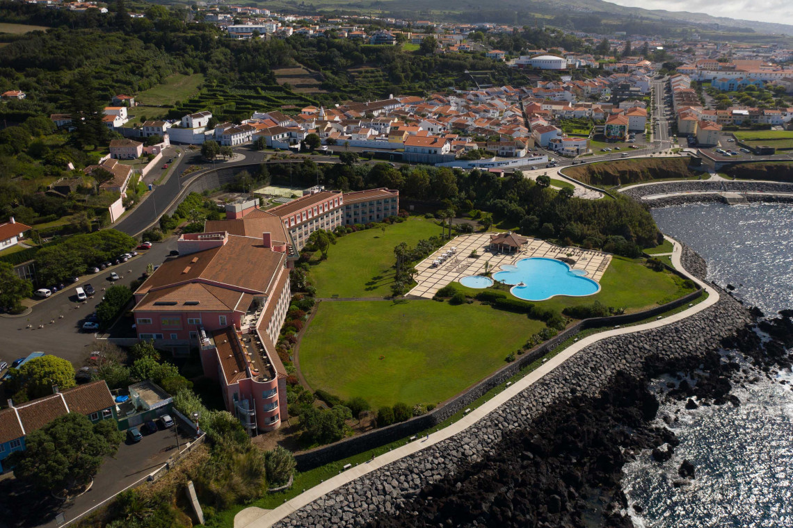Aerial view of Terceira Mar Hotel in Angra do Hero&iacute;smo, showing the hotel building, landscaped grounds and outdoor swimming pool beside the rocky Atlantic coastline of Terceira Island.
