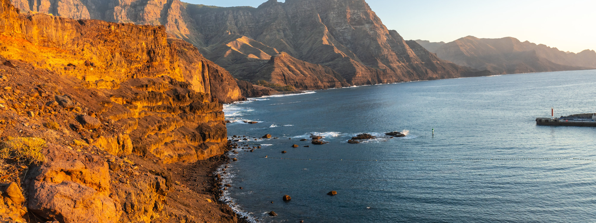 The towering volcanic cliffs of Los Gigantes stretch along Tenerife’s western coast, illuminated by warm evening light above the Atlantic Ocean.